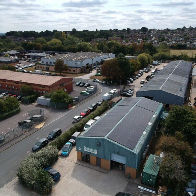 Aerial view of solar panels installed by EVR Ltd on industrial warehouse rooftops in Swindon, Wiltshire, South West England, surrounded by parking areas, greenery, and nearby business units.
